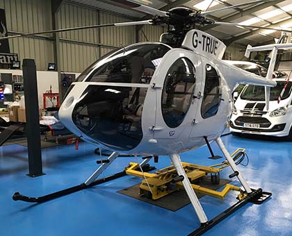 chopper spotter sitting below a helicopter in a hangar