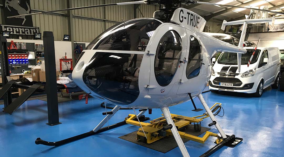chopper spotter sitting below a helicopter in a hangar