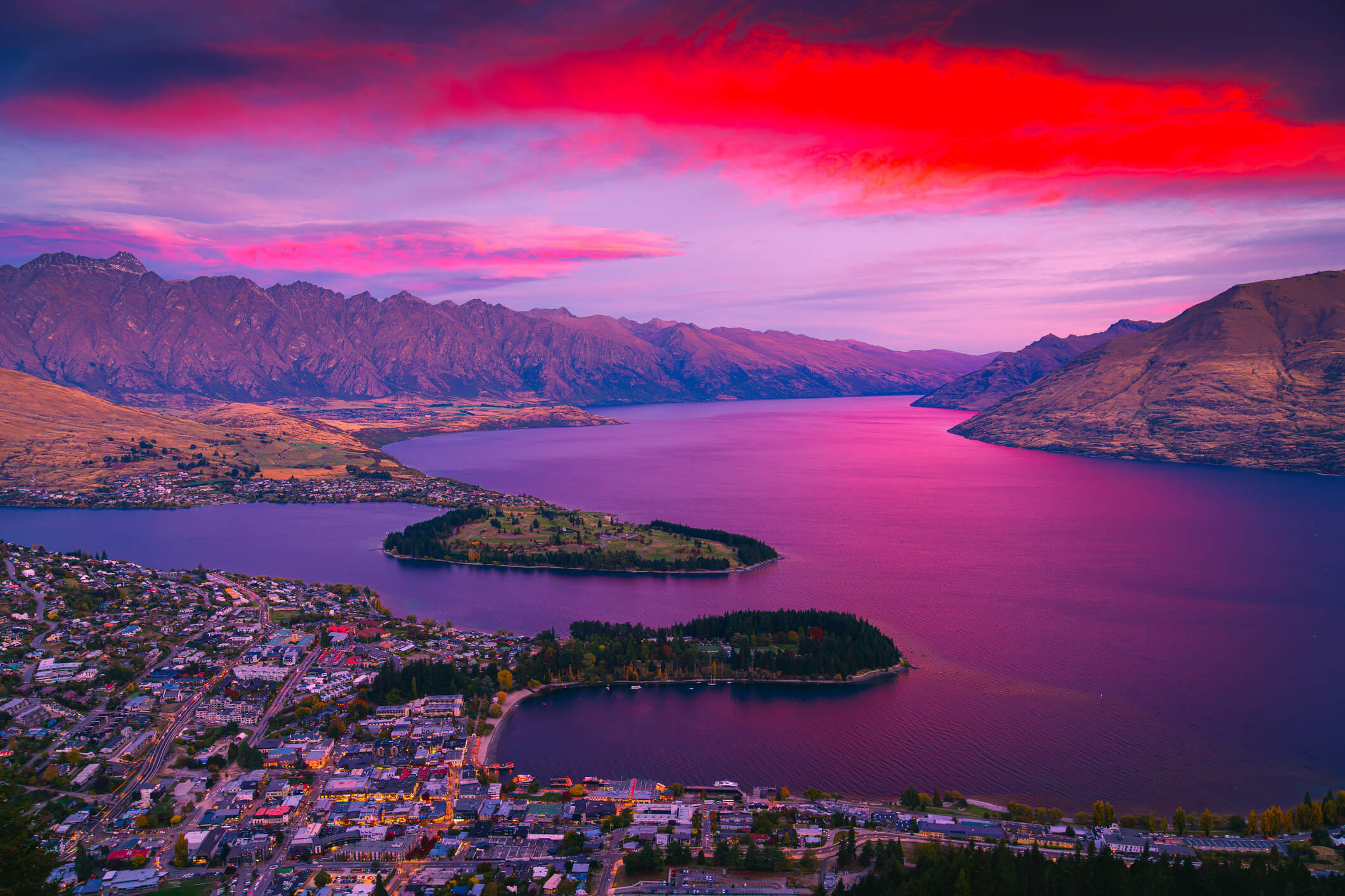 New Zealand, South Island, Queenstown, Lake Wakatipu. Scenic dusk view of illuminated Queenstown cityscape at beautiful sunset with Lake Wakatipu and The Remarkables mountain range, Queenstown, famous resort town in Otago Region, South Island, New Zealand.