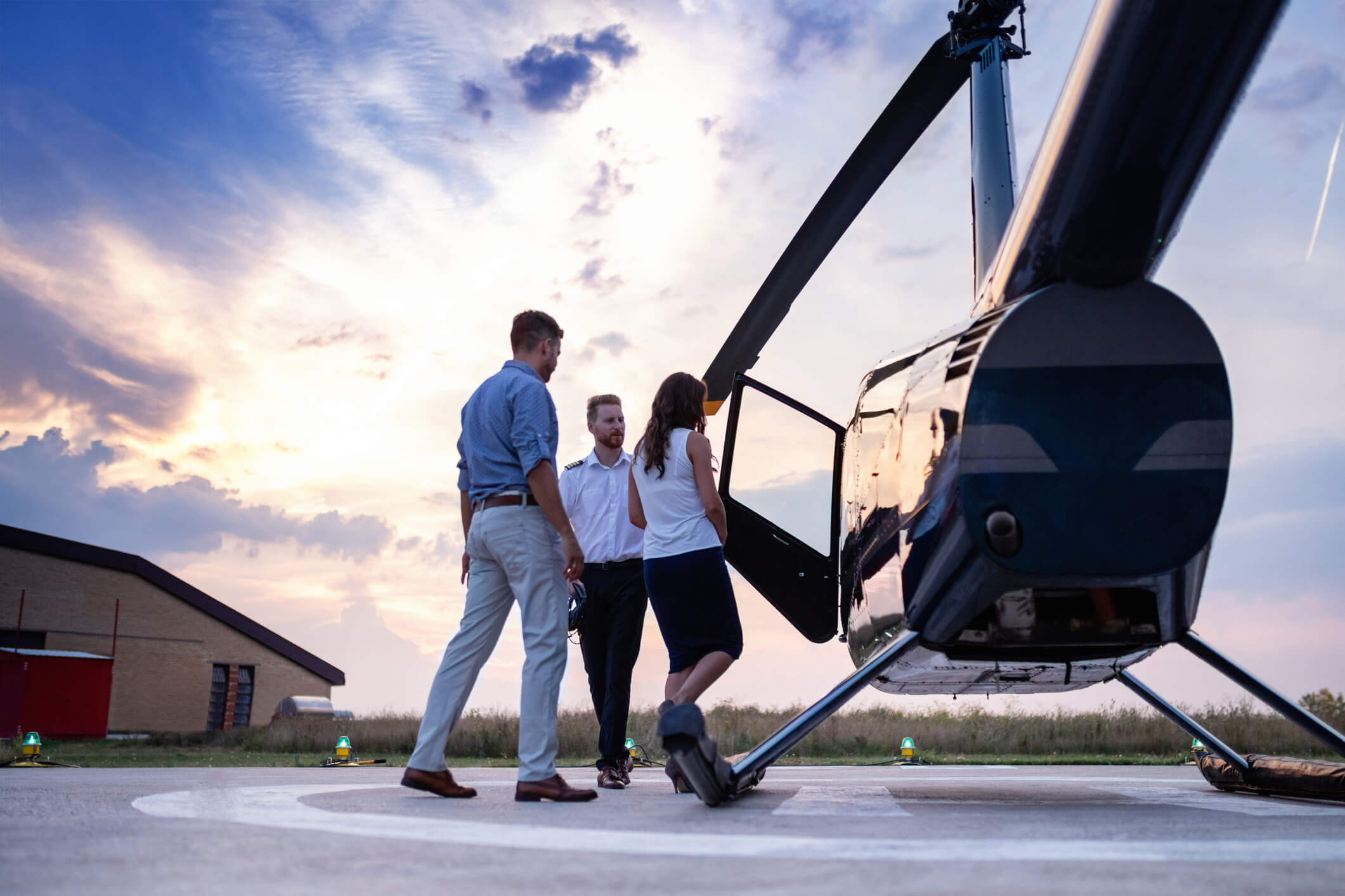 Chopper pilot reaching for handshake while greeting passengers couple